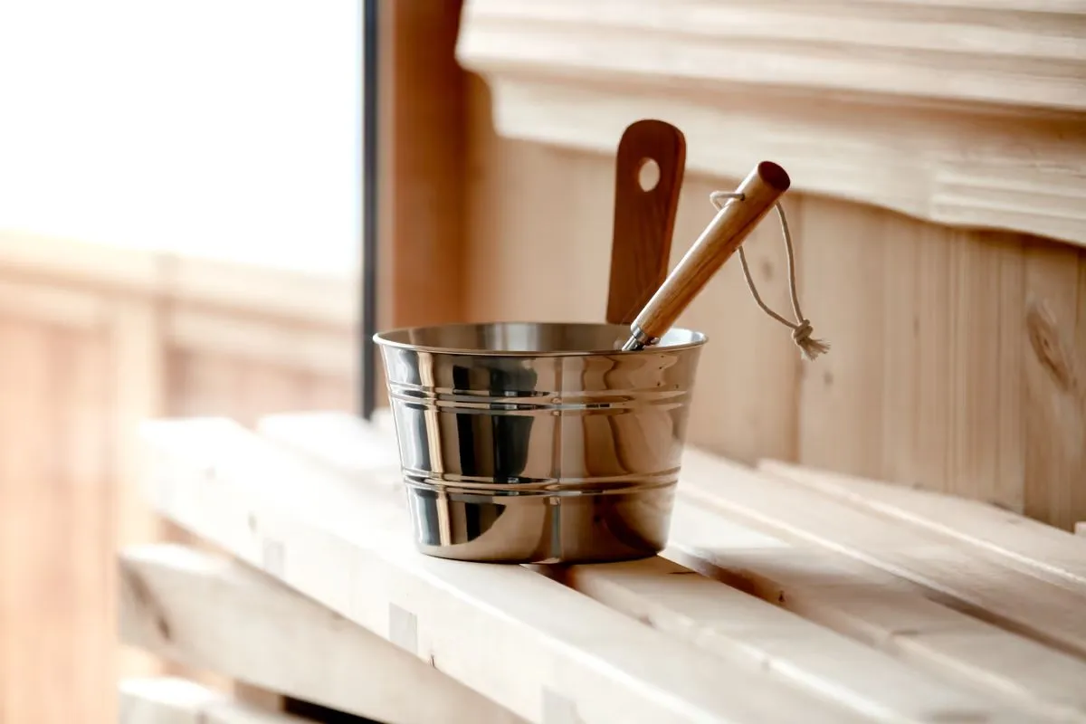 Sauna aus hellem Holz mit Kübel und Kelle