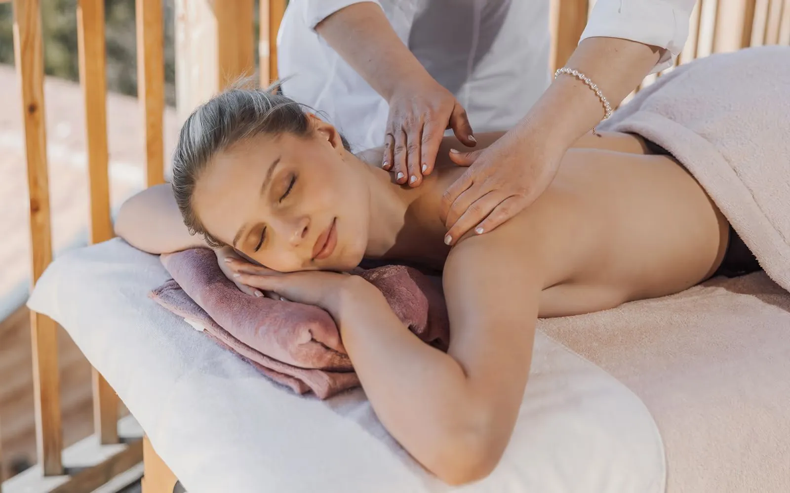 Rückenmassage auf der Liege vor der Holzbrüstung des Balkons
