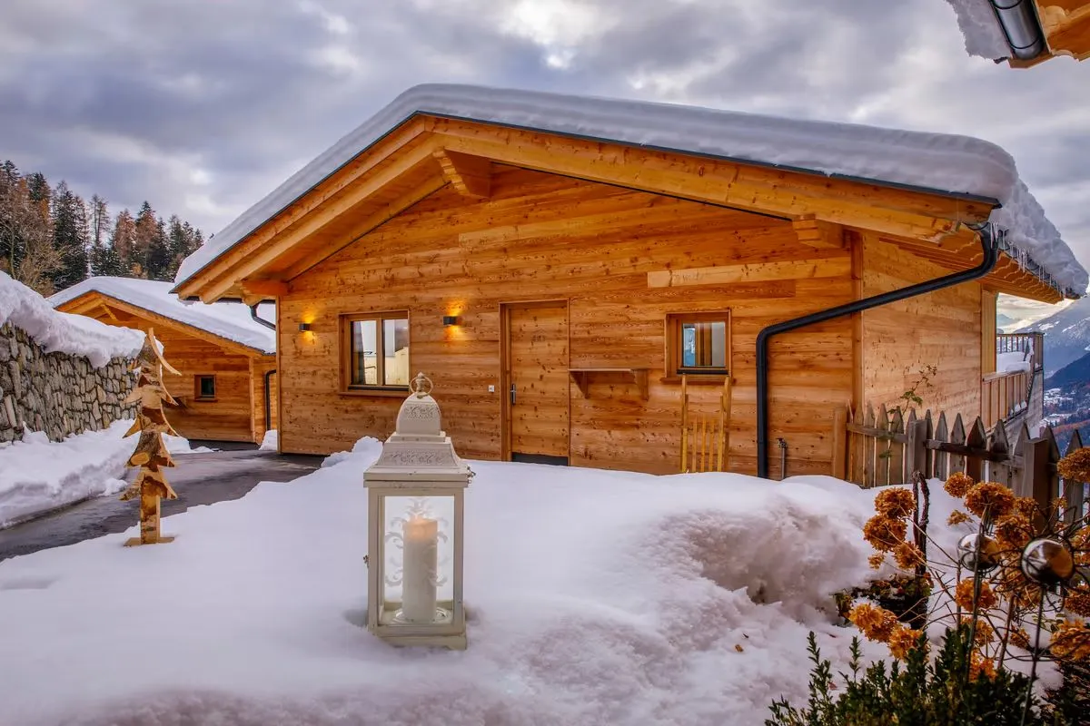 Chalet im Schnee, davor eine brennende Laterne