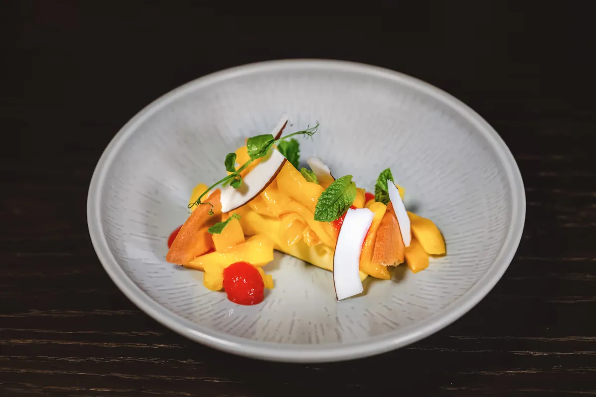 Dessert mit Mangocreme, Kokoschips und Minze