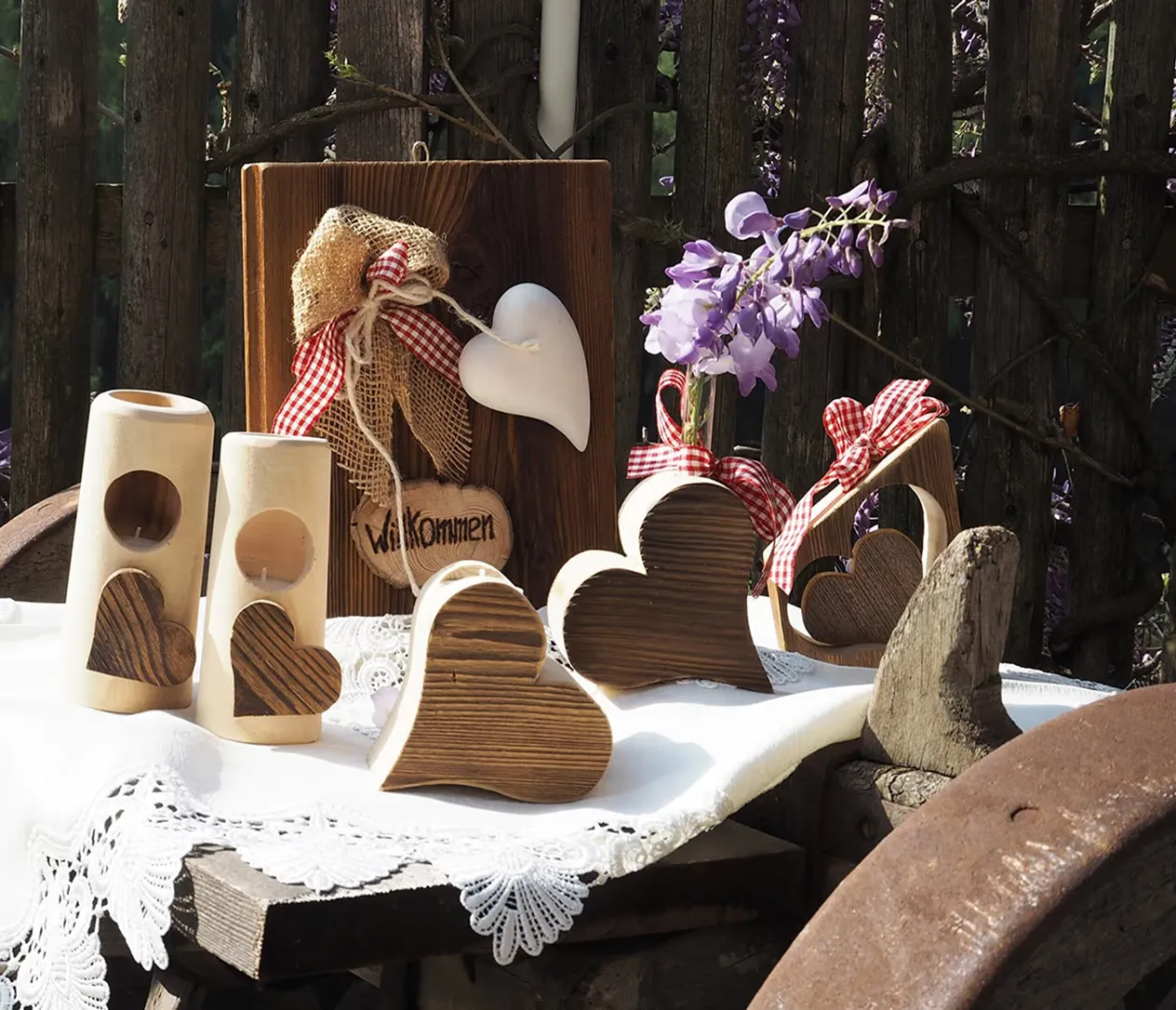 Handgemachte Herzen und Kerzenhalter aus Holz auf einem weißen Spitzendeckchen