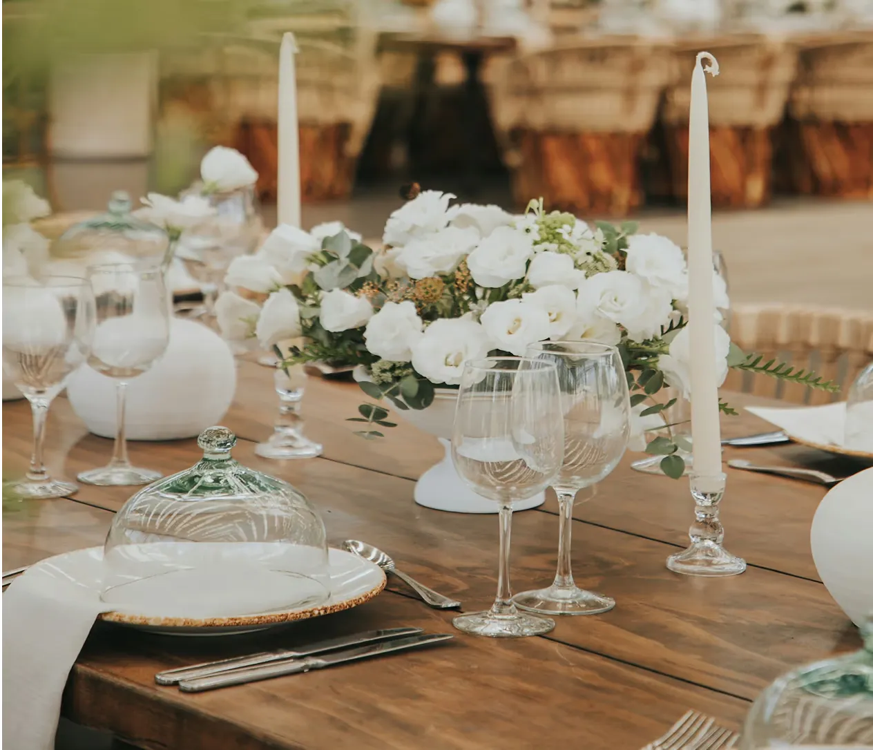 Hochzeitstafel mit weißen Rosen, Kerzen und Gläsern auf Holztisch